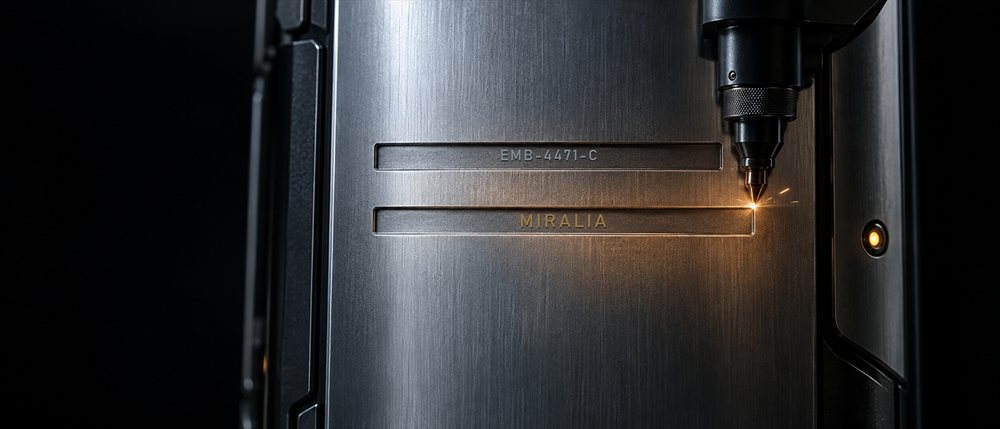 A laser engraving a name under a serial number on a steel capsule, from the film Enter the world